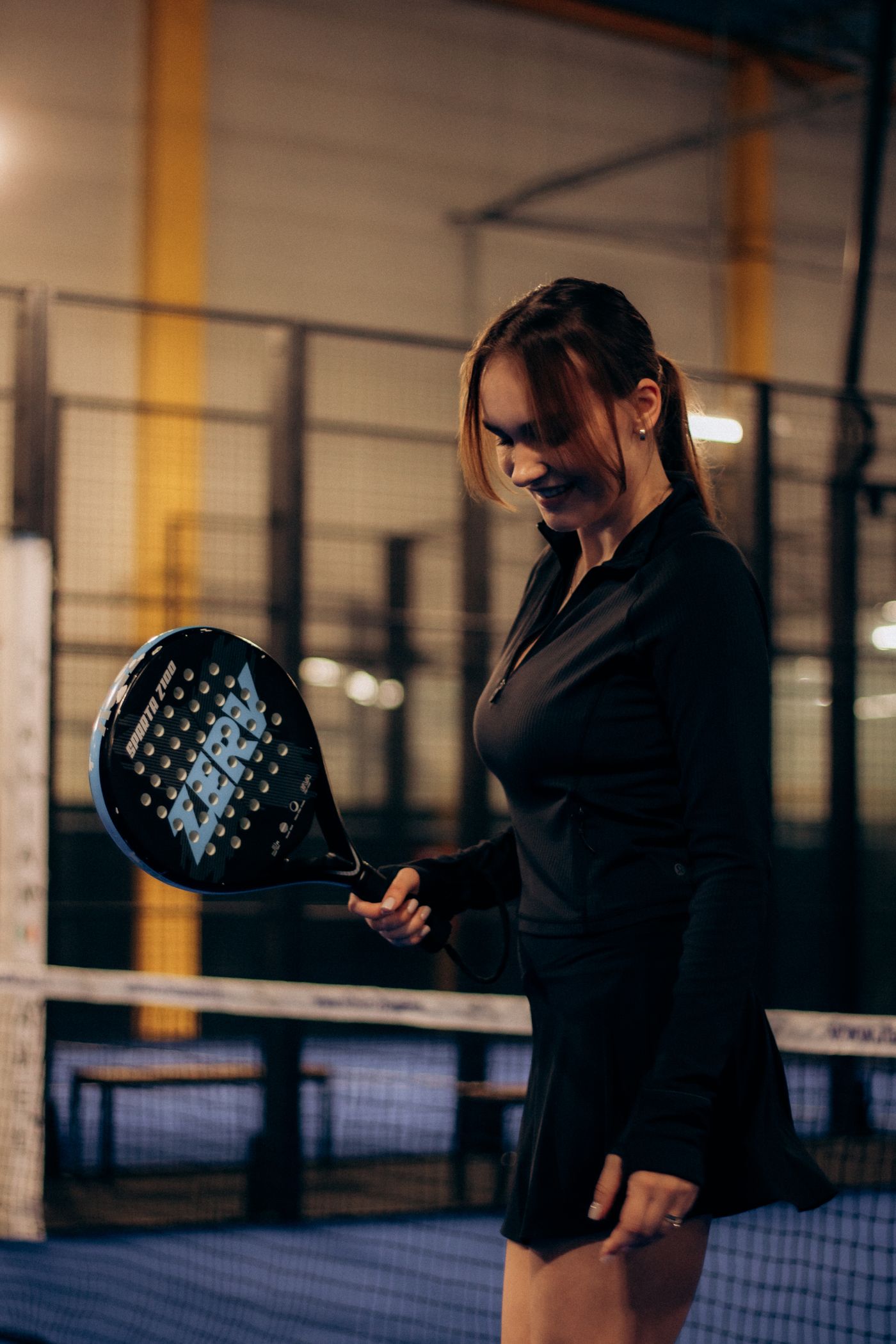 Player holding a padel racket on an indoor court