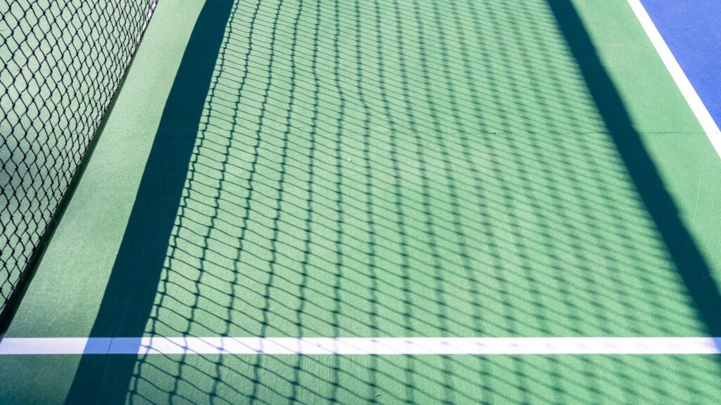 Net and lines of an outdoor pickleball court in sunlight