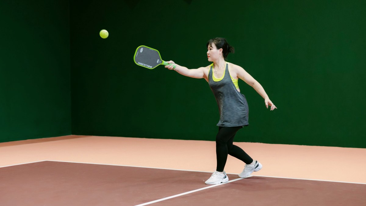 Player stretching for a forehand return on an indoor pickleball court