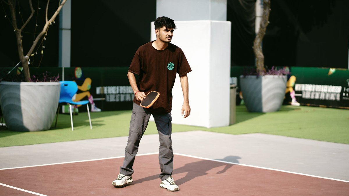 Player standing at the baseline holding a paddle on an outdoor pickleball court