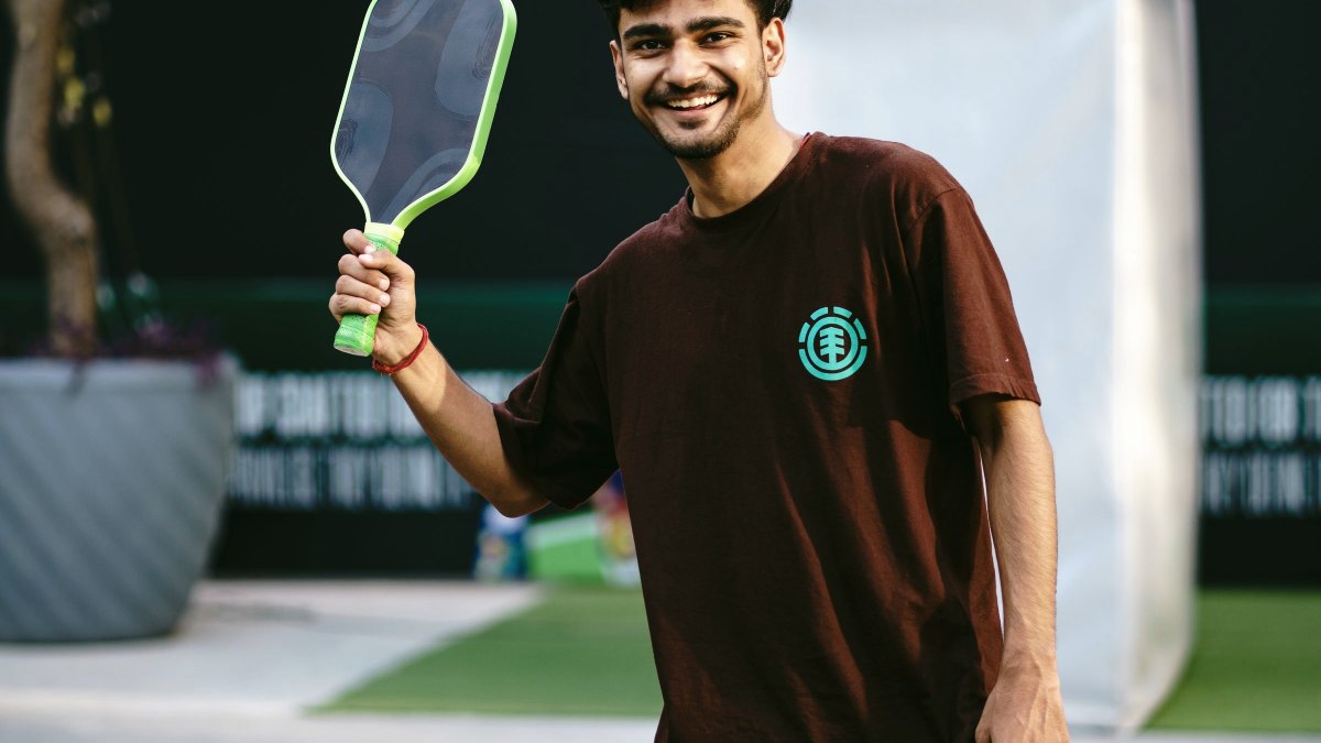 Player holding a pickleball paddle up after winning a point on an outdoor court