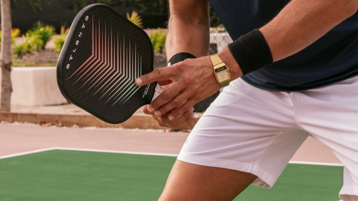 Player in ready position holding a pickleball paddle at chest height on an outdoor court
